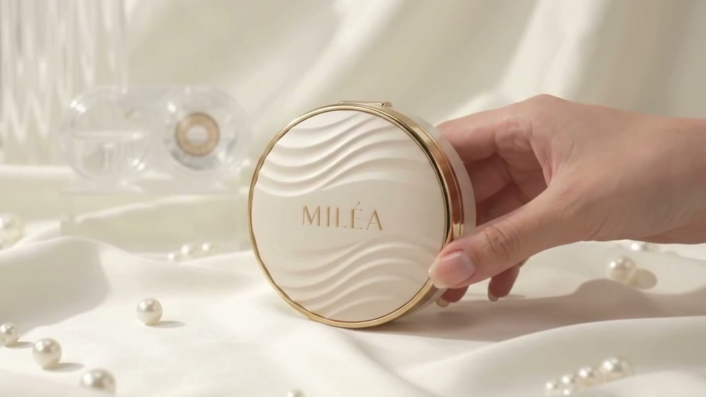 Pearl-white MILÉA lens compact with gold rim, surrounded by pearls